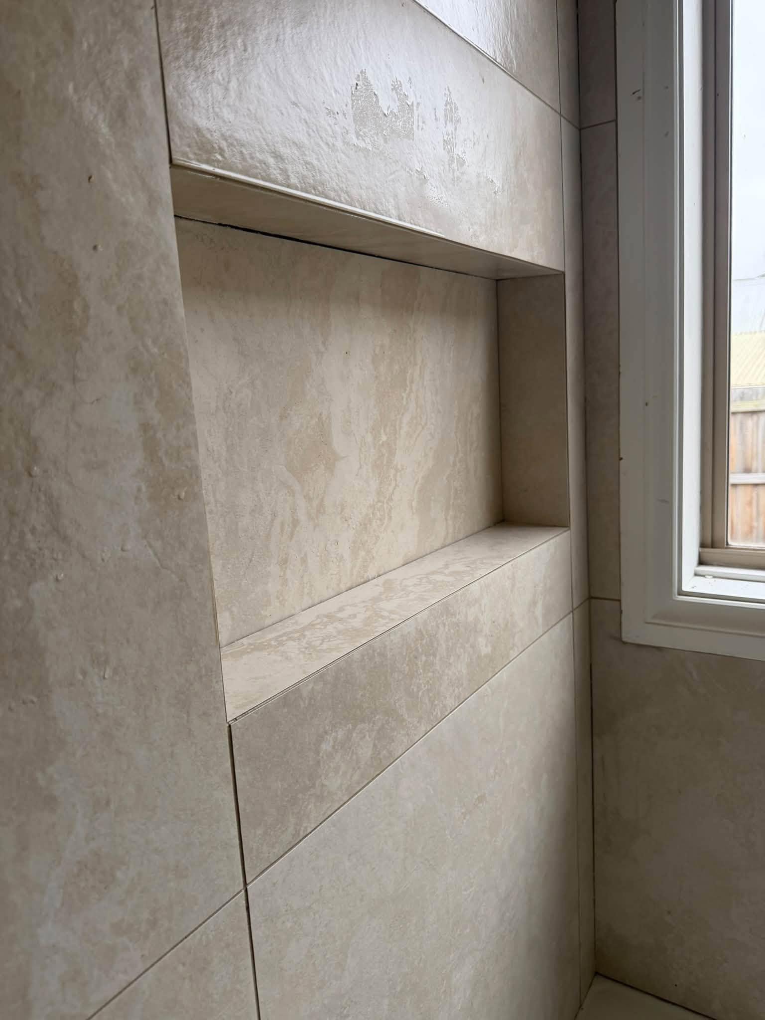 Tiled shower niche with mitred returns in travertine-look porcelain